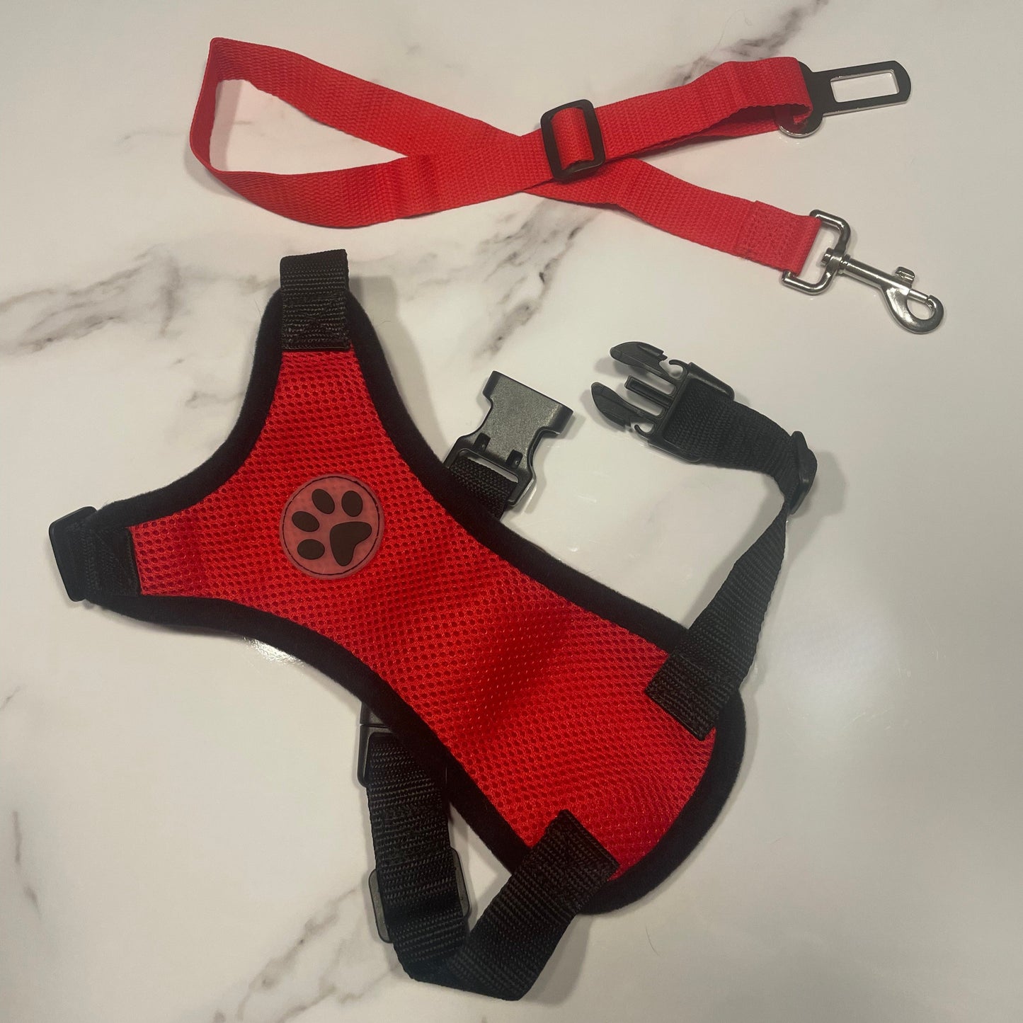Red dog harness with black padding on a marble surface
