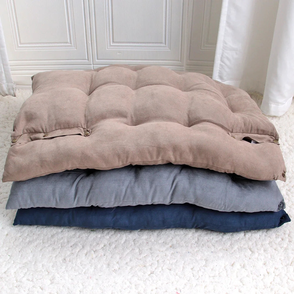 Stack of three folded blankets in brown, gray, and blue on a white floor.